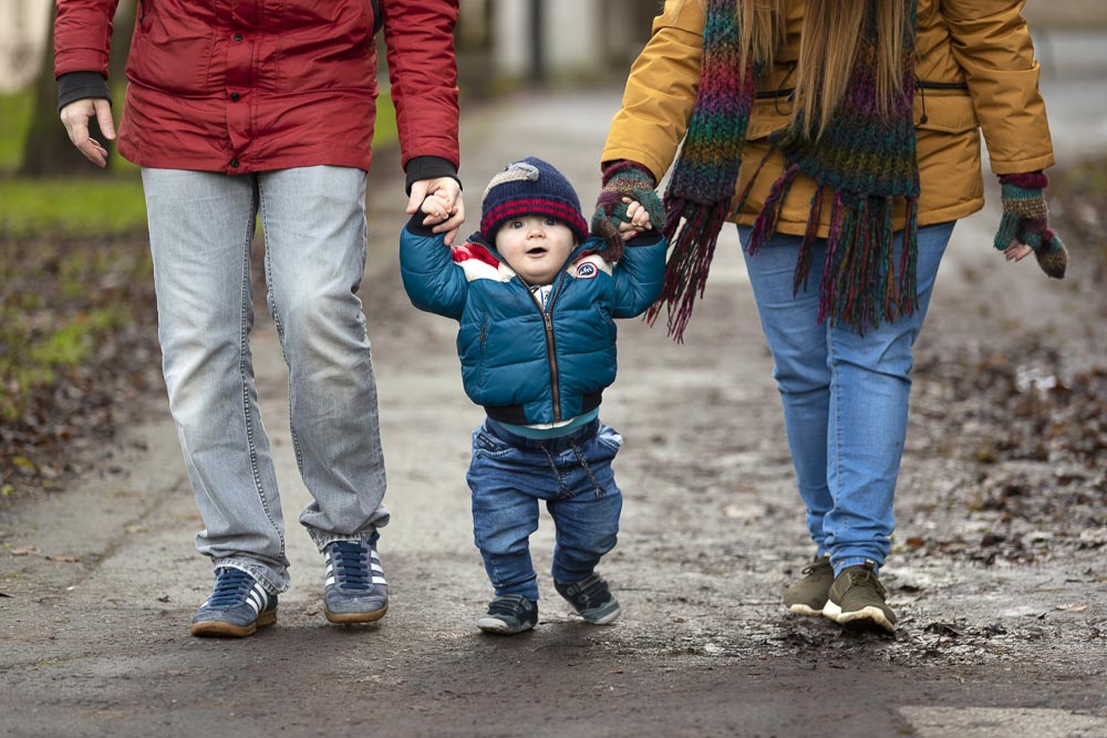 child walking with two adults